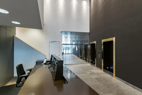 Moderne ontvangsthal met balie, meerdere liften en een spiegelwand in een kantoorpand aan de Grote Marktstraat.